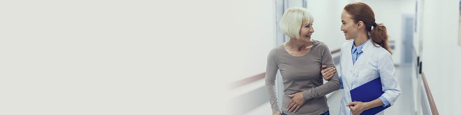 A nurse walking with an elderly woman
